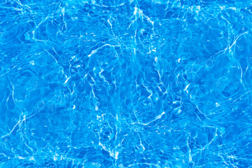 Blue water with ripples on the surface. Defocus blurred transparent blue colored clear calm water surface texture with splashes and bubbles. Water waves with shining pattern texture background.