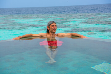 Tranquil closeup calm sea water waves with palm trees. Man tourist posing, Tropical island beach landscape exotic shore coast. Summer vacation, holiday amazing nature. Relax paradise, Maldives.