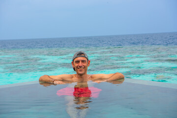 Tranquil closeup calm sea water waves with palm trees. Man tourist posing, Tropical island beach landscape exotic shore coast. Summer vacation, holiday amazing nature. Relax paradise, Maldives.