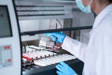 A clinical laboratory scientist loads a sample rack into a high-throughput chemistry analyzer. This...