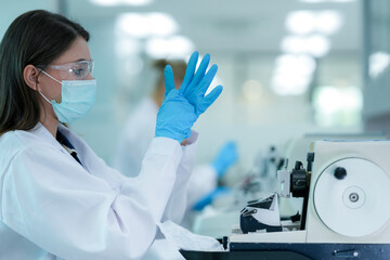 A histotechnologist dons sterile nitrile gloves, following aseptic technique and safety protocols before operating a microtome to section tissue specimens in a pathology laboratory.