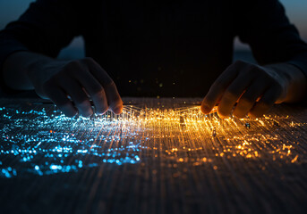 Hands manipulating glowing fiber optic strands, creating a vibrant contrast between blue and orange light on a textured surface.