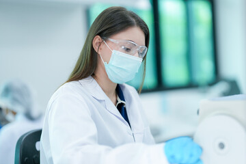A histotechnologist dons sterile nitrile gloves, following aseptic technique and safety protocols before operating a microtome to section tissue specimens in a pathology laboratory.