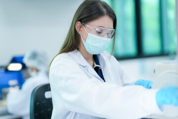 A histotechnologist dons sterile nitrile gloves, following aseptic technique and safety protocols before operating a microtome to section tissue specimens in a pathology laboratory.