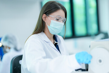 A histotechnologist dons sterile nitrile gloves, following aseptic technique and safety protocols before operating a microtome to section tissue specimens in a pathology laboratory.