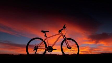 Obraz premium Photograph of a bicycle parked on a hill at sunset. the sky is a beautiful orange and red color, with the sun setting in the background.