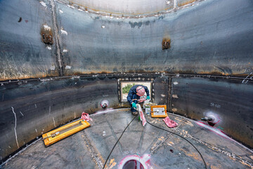 Top view male climbs up the stairs into the tank stainless chemical area inside