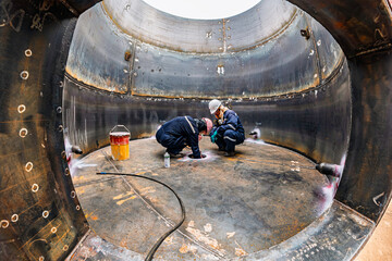 Top view male climbs up the stairs into the tank stainless chemical area inside