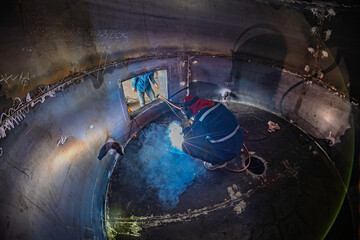 Welding male worker metal is part of machinery bottom plate tank construction flash spark inside...