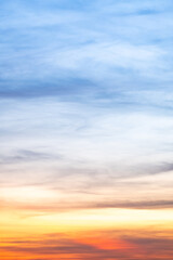 Sunset or sunrise sky with a vibrant gradient of orange, gold, and soft blue. Clear atmosphere with wispy clouds. Peaceful, natural light background. hope, freedom, new day Concepts, Vertical