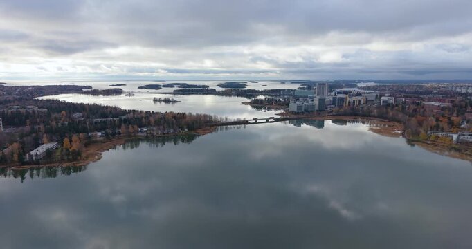 Drone flight over lagoon descending toward modern office buildings in Espoo