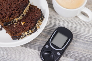 Glucose meter, sweet chocolate cake and cup of coffee with milk. Checking sugar level during diabetes