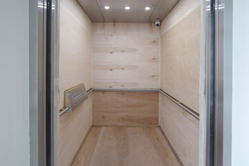 Interior of a passenger lift fitted with temporary plywood boards to prevent damage during construction period