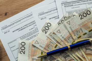 Obraz premium Polish PIT-11 tax form with 200 zloty banknotes, personal income tax and finance concept in Poland