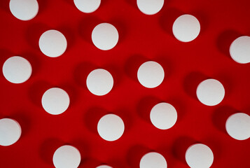 Dense field of white round tablets covering a red surface, minimal texture shot for backgrounds and health concepts. High quality photo