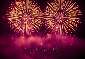 Two fireworks exploding in the night sky with pink smoke below