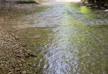 A narrow gorge through which a river flows, the sun's rays break through the upper part of the canyon, illuminating the walls