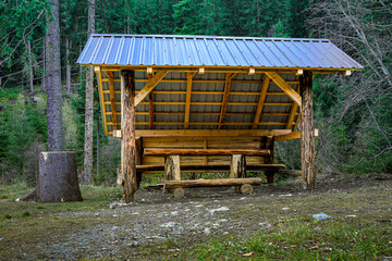 Rustic wooden shelter with benches and table built into the forest for trekkers