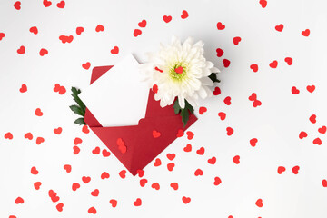 One red envelope, white card, heart-shaped confetti and white flower on white background. Valentine's Day, Mother's Day, Women's Day, Wedding, Anniversary, or Birthday.  Flat lay with copy space.