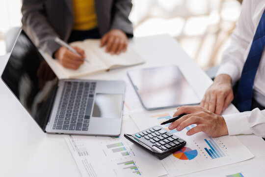 Team og Business work on calculator and laptop for do math finance on wooden desk in office and business working background, tax, accounting, statistics and analytical research concept
