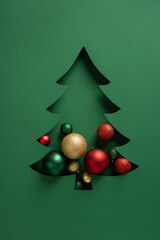 Green card features a tree silhouette cut from the page with shiny red gold and green balls,...