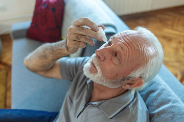 Man putting liquid drops in his eye solving vision problem.Senior dropping eye drop medicine...