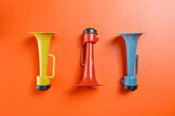 Plastic horn on a red background. Concept of a party or a holiday celebration