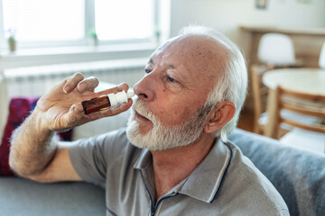 Senior Man is having flu and he is using nasal spray to help herself. Man using nasal spray. Nasal...
