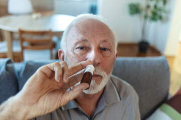 Senior Man is having flu and he is using nasal spray to help herself. Man using nasal spray. Nasal...