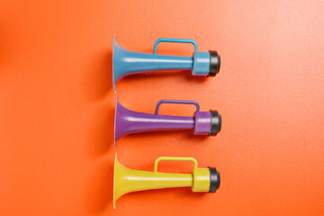 Plastic horn on a red background. Concept of a party or a holiday celebration