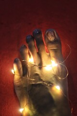 Fairy lights wrapped around left foot and toes on Black or Asian left foot with the following...