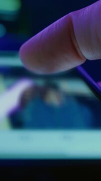 Close-up of a hand holds smartphone and scrolling through social media in dark room, symbolizing late-night doom scrolling and digital addiction habits. Vertical video