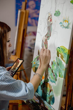 Woman painting on canvas with a brush during an art workshop. Artistic practice supports learning, creativity, mindfulness and personal growth.
