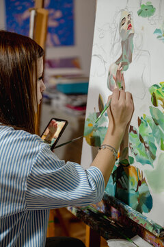 Woman painting on canvas with a brush during an art workshop. Artistic practice supports learning, creativity, mindfulness and personal growth.