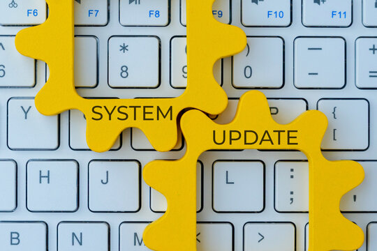 Two interlocking gear with text SYSTEM UPDATE on a computer keyboard. Improvement, maintenance, or software upgrade concept.