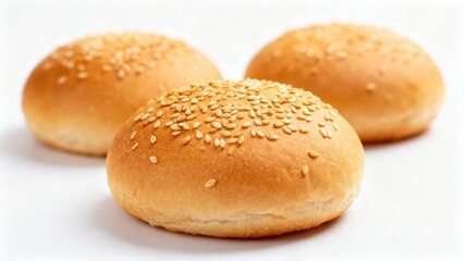 Three golden baked round bread rolls generously sprinkled with sesame seeds sit on a white surface.