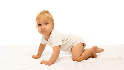 Fototapeta premium Curious baby crawling on white bed exploring surroundings with focus and gentle determination. Concept of growth, development, and exploration in early childhood learning.