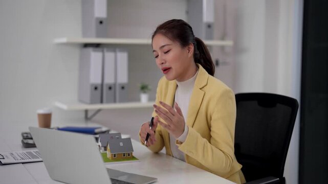 Adult Asian woman real estate agent working laptop computer office property house models sales transaction investment consultant financial planning business professional service