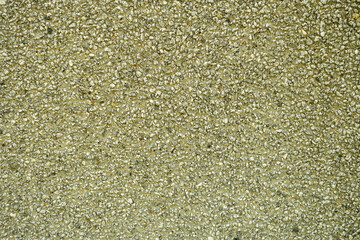 Texture of green rough concrete with small embedded pebbles, uneven surface