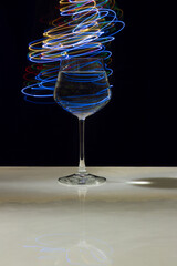 Wine glass with water and neon light on marble table and black background