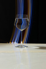 Wine glass with water and neon light on marble table and black background