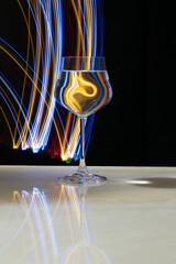 Wine glass with water and neon light on marble table and black background