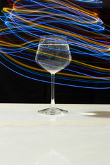 Wine glass with water and neon light on marble table and black background