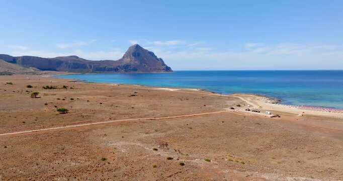 Aerial view of Macari Beach, located near San Vito Lo Capo in Sicily, Italy. In the background is a mountain called Monte Cofano, and the turquoise sea in the foreground.