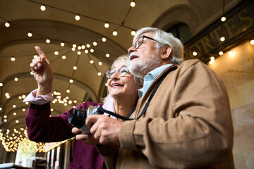 Senior couple traveling pointing discovery city lights