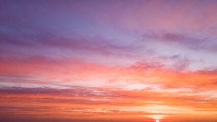 Obraz premium Vibrant clouds paint the sky with orange, pink, and purple hues at sunset.