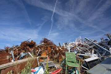 Stacked Pile Of Scrap Metal And Broken Chairs In A Junkyard Under A Bright Blue Sky