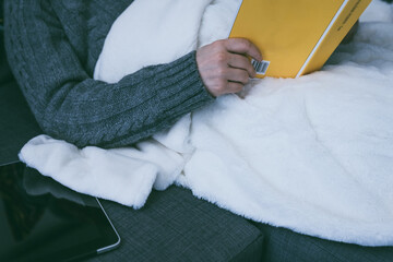 Paper books vs ebooks. Woman reads a physical book, tablet sits unused. Pleasure of traditional reading