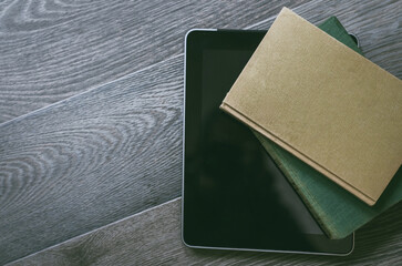 Traditional vs digital reading. Two paper books beside a modern tablet on a wood surface, Evolution of literature, information access concept. Ideal for articles on reading, technology, or education.