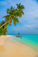 Tranquil closeup calm sea water waves with palm trees. Woman tourist swinging, Tropical island beach landscape exotic shore coast. Summer vacation, holiday amazing nature. Relax paradise, Maldives.
